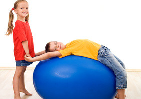 Kids doing gymnastic exercises with a large rubber ball having fun together - isolated